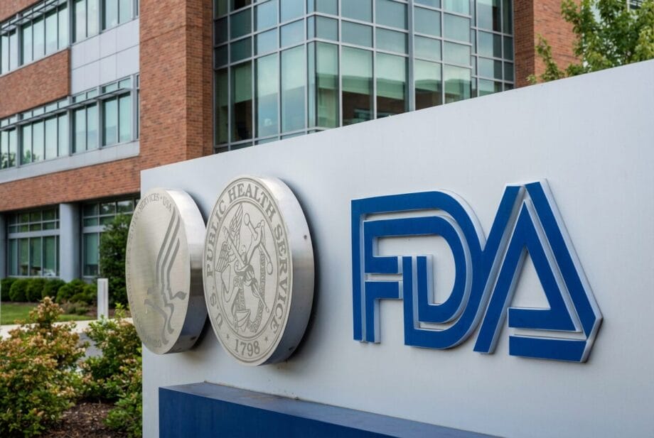 A close-up of the FDA sign outside a modern brick and glass building, with agency seals visible on the sign.