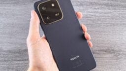 Hand holding a dark blue smartphone with camera module.