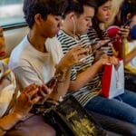 people using smartphones while sitting inside train