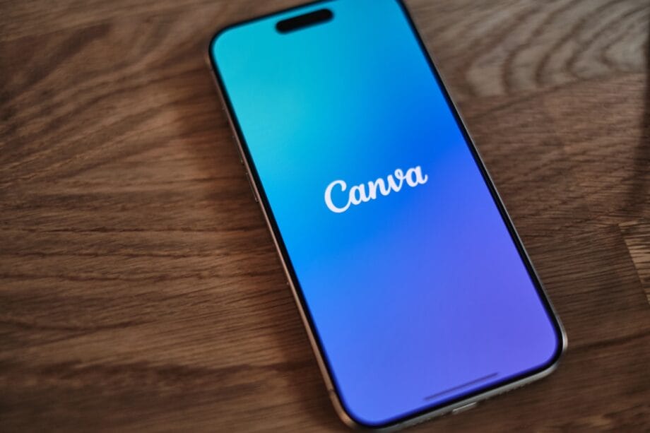 A smartphone displaying the Canva app logo on its screen rests on a wooden surface.