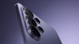 Close-up of the rear camera lenses and side buttons on a modern smartphone with a metallic finish, set against a gradient background.