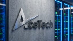 Metallic AceTech logo on a concrete wall next to illuminated server racks in a modern data center environment.