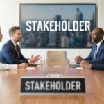 Four business professionals sit at a conference table with a STAKEHOLDER sign and presentation screen in a modern office.