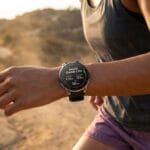 Person jogging on a dirt trail while wearing a smartwatch that displays fitness data on their wrist.