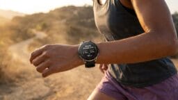 Person jogging on a dirt trail while wearing a smartwatch that displays fitness data on their wrist.