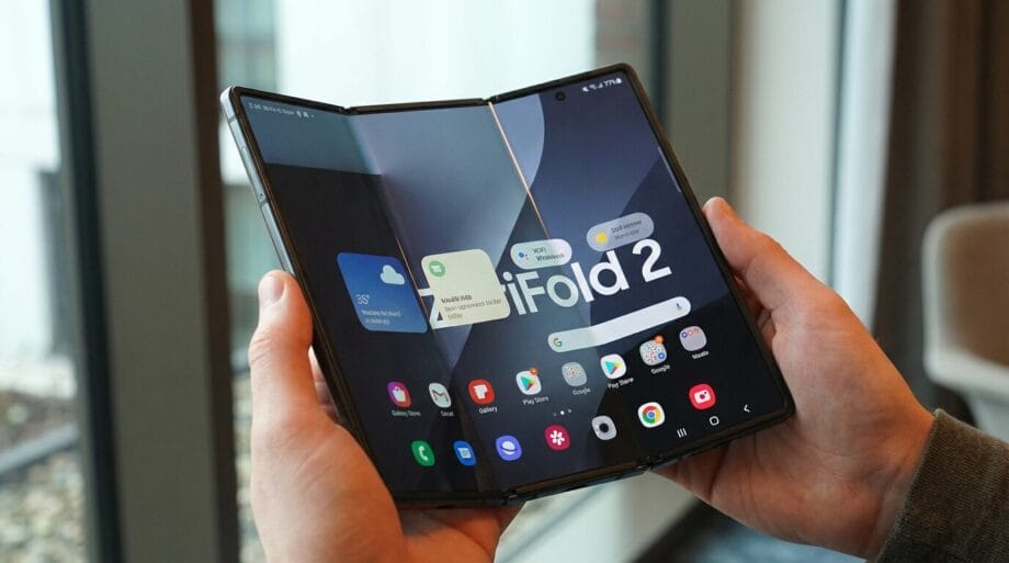 Person holding an open foldable smartphone displaying its main home screen with various app icons and a large &ldquo;Fold 2&rdquo; on the display.