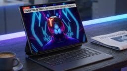 A tablet with a keyboard displays a news segment about the Legion Y900 tablet, featuring a futuristic graphic, on an office desk with coffee.