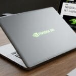 A silver laptop with a glowing NVIDIA N1 logo sits on a desk beside a tablet displaying news about the NVIDIA N1 laptop.