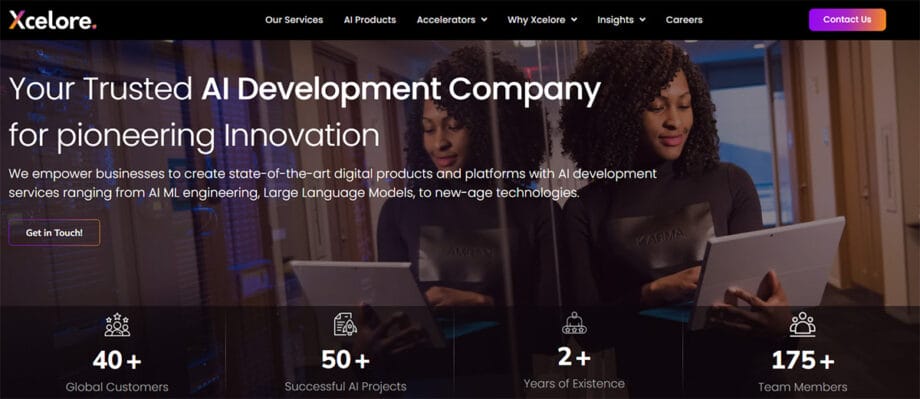 A woman with curly hair uses a tablet in a modern office. Text promotes Xcelore’s AI development services and company statistics.