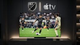 A television displays a soccer match beneath MLS and Apple TV logos, with a streaming device and remote on the shelf below.